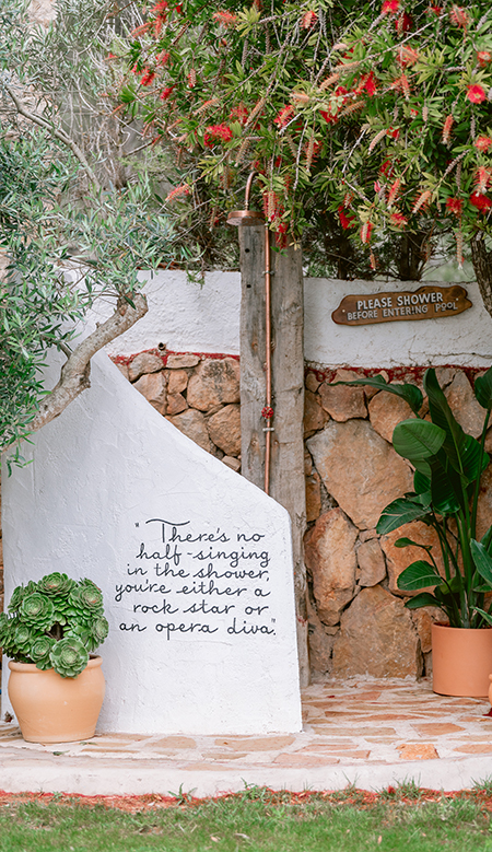 Covered terrace at Casa Naya Ibiza with natural fiber lamps, a wooden dining table, and handcrafted décor.